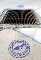 USU students stencil storm drains with warning labels